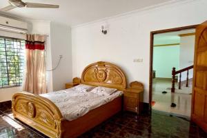 um quarto com uma cama de madeira e um espelho em Kumar Para Deluxe Villa em Sylhet