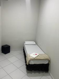 a small bedroom with a bed in a white room at Hostel São João in Araçariguama