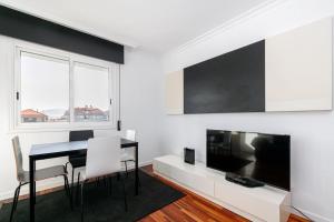 a white living room with a table and a television at Moderno piso en el corazón de Baiona by CABANA Rentals in Baiona