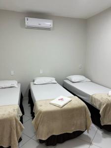 - une chambre avec 3 lits et des serviettes dans l'établissement Hostel São João, à Araçariguama