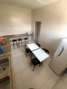 eine Küche mit Tischen und Stühlen sowie einem Kühlschrank in der Unterkunft Hostel São João in Araçariguama