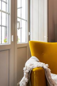 una silla amarilla con una manta junto a una ventana en Victoria Seis, en Medina Sidonia