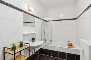 y baño blanco con lavabo y bañera. en Homespace - Magdeburg - Gemütliches Apartment mit Balkon en Magdeburgo