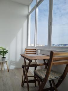 una mesa de madera y 2 sillas frente a una ventana en Beach Apartment w/Ocean view en Costa da Caparica