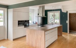 eine Küche mit weißen Schränken und einer hölzernen Arbeitsplatte in der Unterkunft Nice Home In Lyngdal With House A Panoramic View in Lyngdal