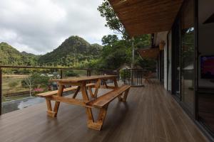 uma mesa de piquenique de madeira num deque com montanhas ao fundo em YEN Hidden Valley em Ilha de Cát Bà