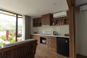 a kitchen with wooden cabinets and a large window at YEN Hidden Valley in Cat Ba