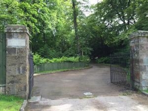 an entrance to a driveway with a gate and trees at Limefield House in Livingston