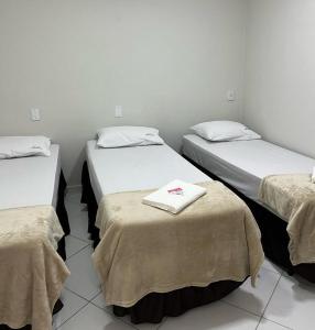 a room with three beds with towels on them at Hostel São João in Araçariguama