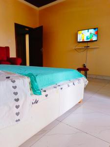 a bed in a room with a tv on a wall at Kigali Peace vill in Kigali