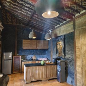 a kitchen with wooden cabinets and a large mural of a head at Beyond Heaven in Tampaksiring