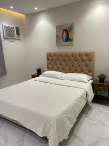 a bedroom with a large bed with white sheets and a headboard at شقة بيروت 2 in Riyadh
