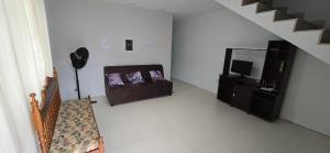 uma sala de estar com um sofá e uma televisão em Casa Temporada Barra-Mar em Guriri
