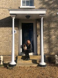 una mujer sentada en una puerta con un perro en Yew Tree House, Bed & Breakfast in Colchester, en Lexden