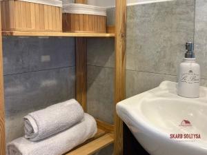 a bathroom with a sink and towels on a shelf at Skarb Sołtysa - apartament z widokiem in Jedwabno +10 photos