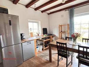 a kitchen and dining room with a table and a refrigerator at Skarb Sołtysa - apartament z widokiem in Jedwabno