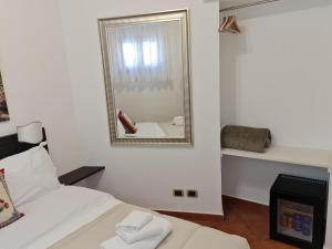 Dormitorio blanco con espejo y cama en B&B RE TANCREDI en Taormina