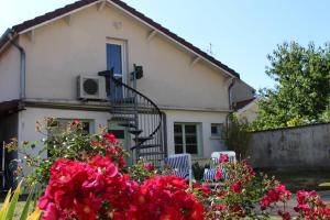 a white house with red flowers in front of it at Meublé 2* climatisé dans un quartier calme in Dijon