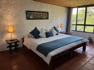 a bedroom with a large bed with blue pillows at Finca Hotel Sol Y Luna in Calarcá