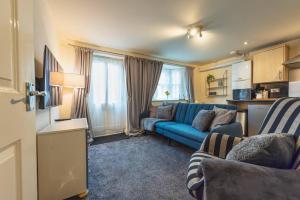 a living room with a blue couch and a kitchen at Pass the Keys Modern Ground Floor Apartment in Shifnal