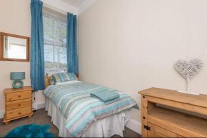 a bedroom with a bed with blue curtains and a window at Bright 2 Bedroom Apartment near Seafront Central Penzance in Penzance