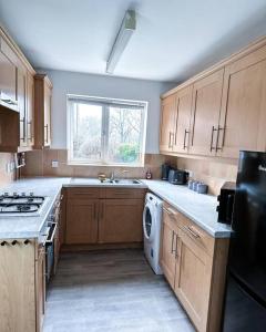 uma cozinha com armários de madeira, um lavatório e uma máquina de lavar louça em Spacious 6 Bedroom House Near City Centre em Birmingham