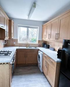 a kitchen with wooden cabinets and a sink and a dishwasher at Spacious 6 Bedroom House Near City Centre in Birmingham