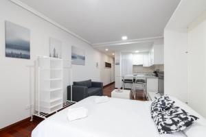 1 dormitorio blanco con 1 cama y cocina en Estudio moderno con parking by CABANA Rentals, en Vigo
