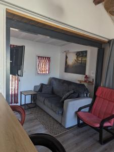 カステルノ・ド・メドックにあるChez les Martinのリビングルーム(グレーのソファ、赤い椅子付)