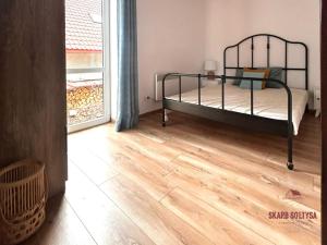 a bedroom with a bed and a wooden floor at Skarb Sołtysa - apartament z widokiem in Jedwabno