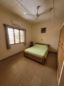 una camera con letto e ventilatore a soffitto di La Belle Vie Là de Ouidah a Ouidah