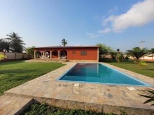 a swimming pool in front of a house at La Belle Vie Là de Ouidah in Ouidah
