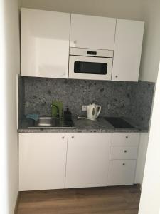 a white kitchen with a sink and a microwave at Penzion nad Bankou in Košice