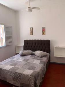 a bedroom with a bed with a blanket and a ceiling fan at Pousada Tropical in Marataizes