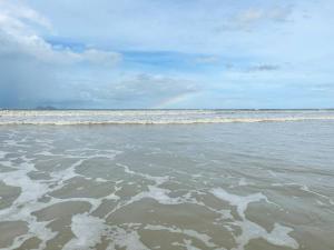 a beach with a rainbow in the water at Beachfront Retreats @RoxyBeachSematanApt. in Sematan