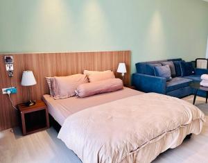 a bedroom with a large bed and a blue couch at Beachfront Retreats @RoxyBeachSematanApt. in Sematan