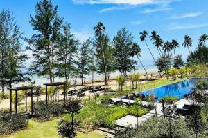 a resort with a swimming pool and palm trees at Beachfront Retreats @RoxyBeachSematanApt. in Sematan