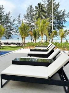 a group of benches sitting on a patio at Beachfront Retreats @RoxyBeachSematanApt. in Sematan