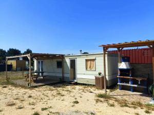 una pequeña casa blanca con toldo y parrilla en Sunset Milfontes, en Vila Nova de Milfontes