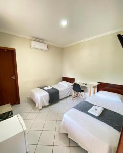 a hotel room with two beds and a desk at Buriti Hotel - Barra do Riacho, Aracruz ES in Aracruz