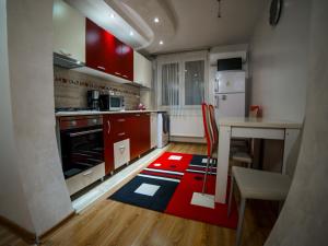 a kitchen with red cabinets and a red rug on the floor at Residence Apartments Deva in Deva