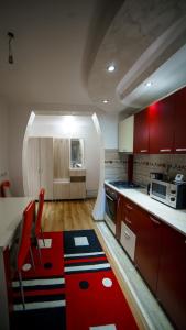 a kitchen with red cabinets and a table with chairs at Residence Apartments Deva in Deva