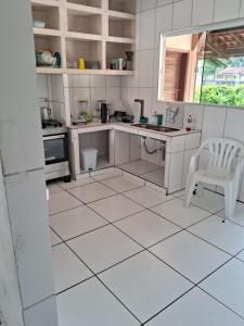 eine Küche mit weißem Fliesenboden, einem Tisch und einem Stuhl in der Unterkunft Sitio in Itapoa