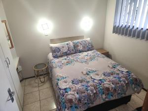 a small bedroom with a bed with a floral bedspread at SurfBay Sands 65 in Shelly Beach