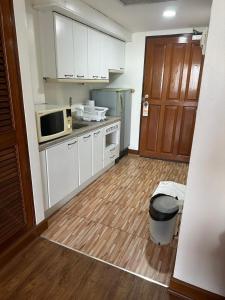 Omni Tower Sukhumvit Soi 4 Direct Rooms في بانكوك: مطبخ بدولاب بيضاء وأرضية خشبية