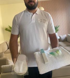 a man in a white shirt holding a towel at Pure Sand - Luxury Hostel JBR Dubai in Dubai