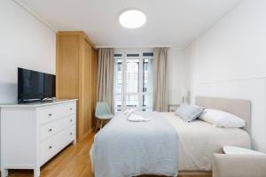 a white bedroom with a bed and a tv at Céntrico y acogedor by CABANA Rentals in Vigo