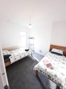 een slaapkamer met 2 bedden en een raam bij Basic 5-bedroom home - Affordable accommodation for groups in Swansea