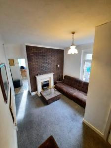 a living room with a couch and a fireplace at Basic 5-bedroom home - Affordable accommodation for groups in Swansea