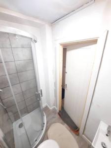 een badkamer met een toilet en een glazen douche bij Basic 5-bedroom home - Affordable accommodation for groups in Swansea